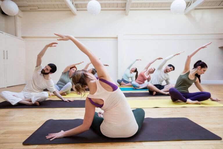 trainer-assisting-group-people-with-stretching-exercise (1)
