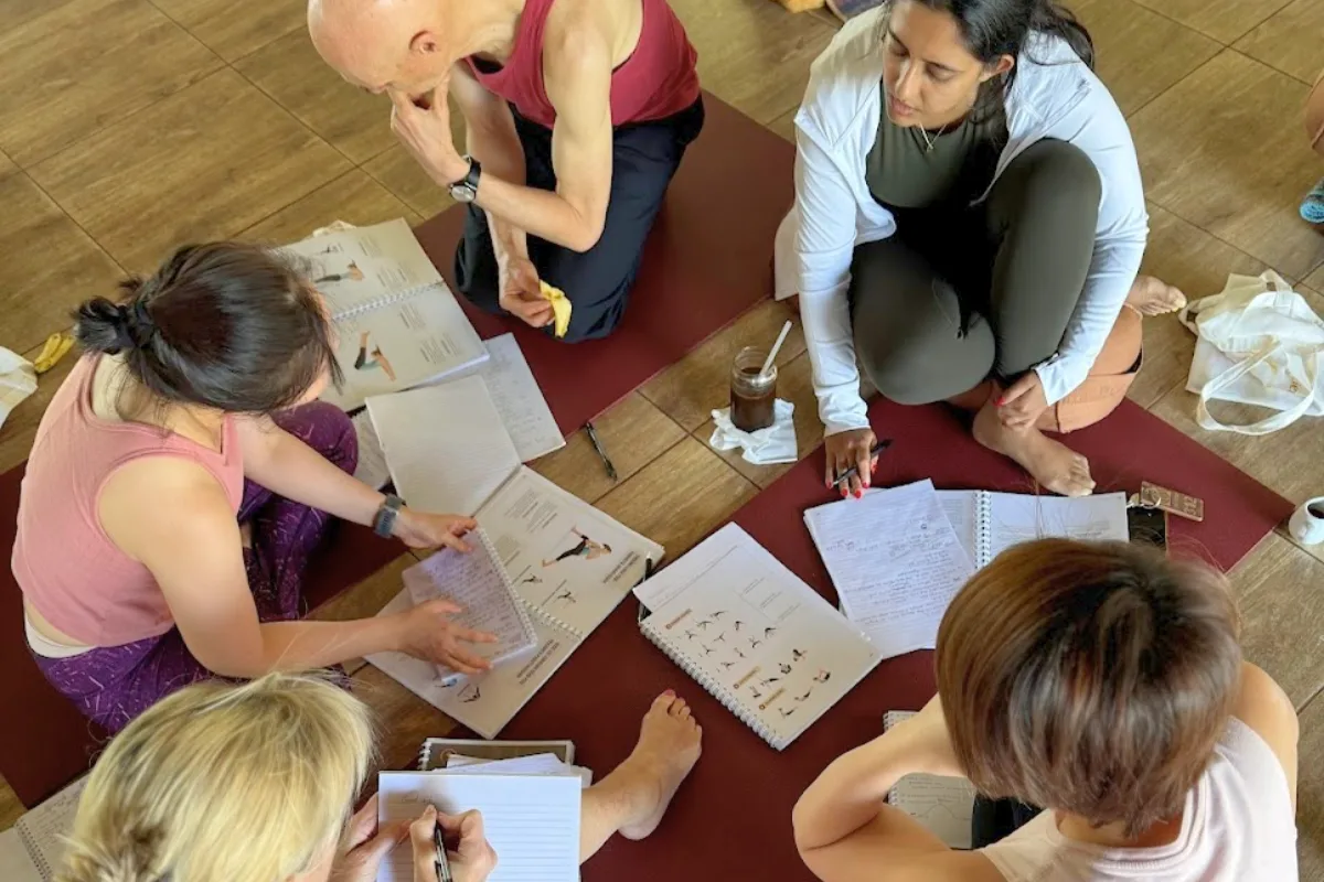 YNV - Small Group Study Circle Reviewing Yoga Manuals on Floor